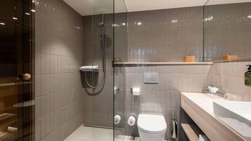 A modern bathroom with a glass-enclosed shower, a toilet, and a vanity with a mirror.