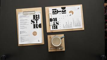 Un menu proposant des plats à base de viande, de poisson ou de boulettes végétaliennes, ainsi qu’une tasse de café sur une table.
