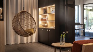 Una habitación moderna con una silla colgante, una estantería empotrada y una mesita con un jarrón.