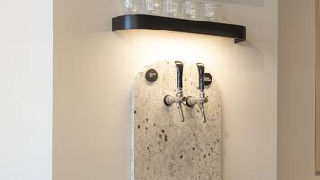 A wall-mounted water dispenser with two taps and a shelf above it holding glasses.