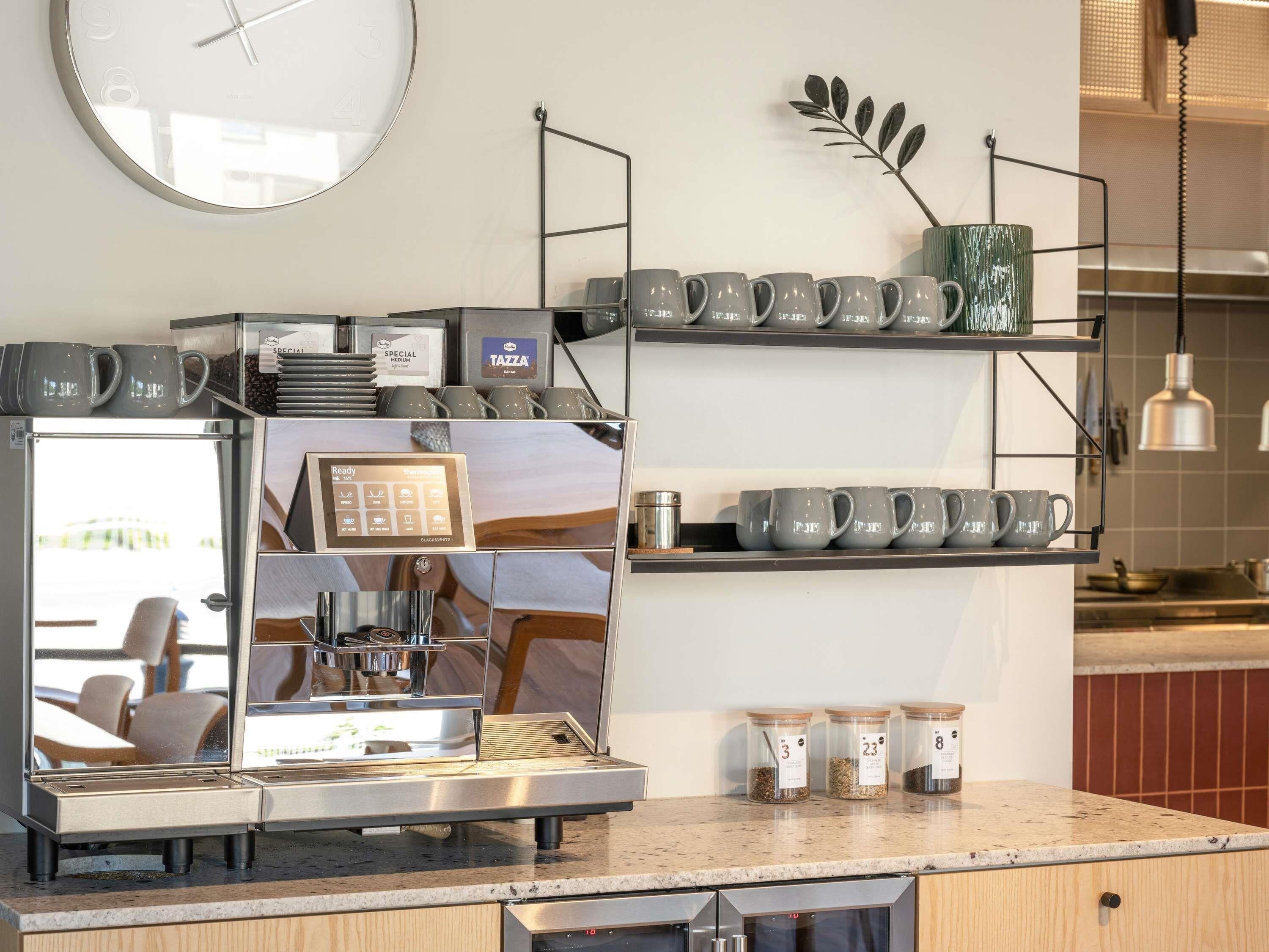 A coffee machine with a digital display, a clock, and shelves with mugs and containers.