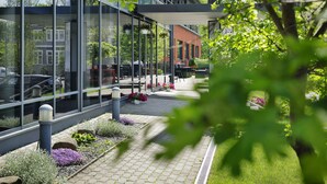Un edificio moderno con amplios ventanales, fachada de ladrillo y un jardín bien cuidado con senderos y parterres de flores.