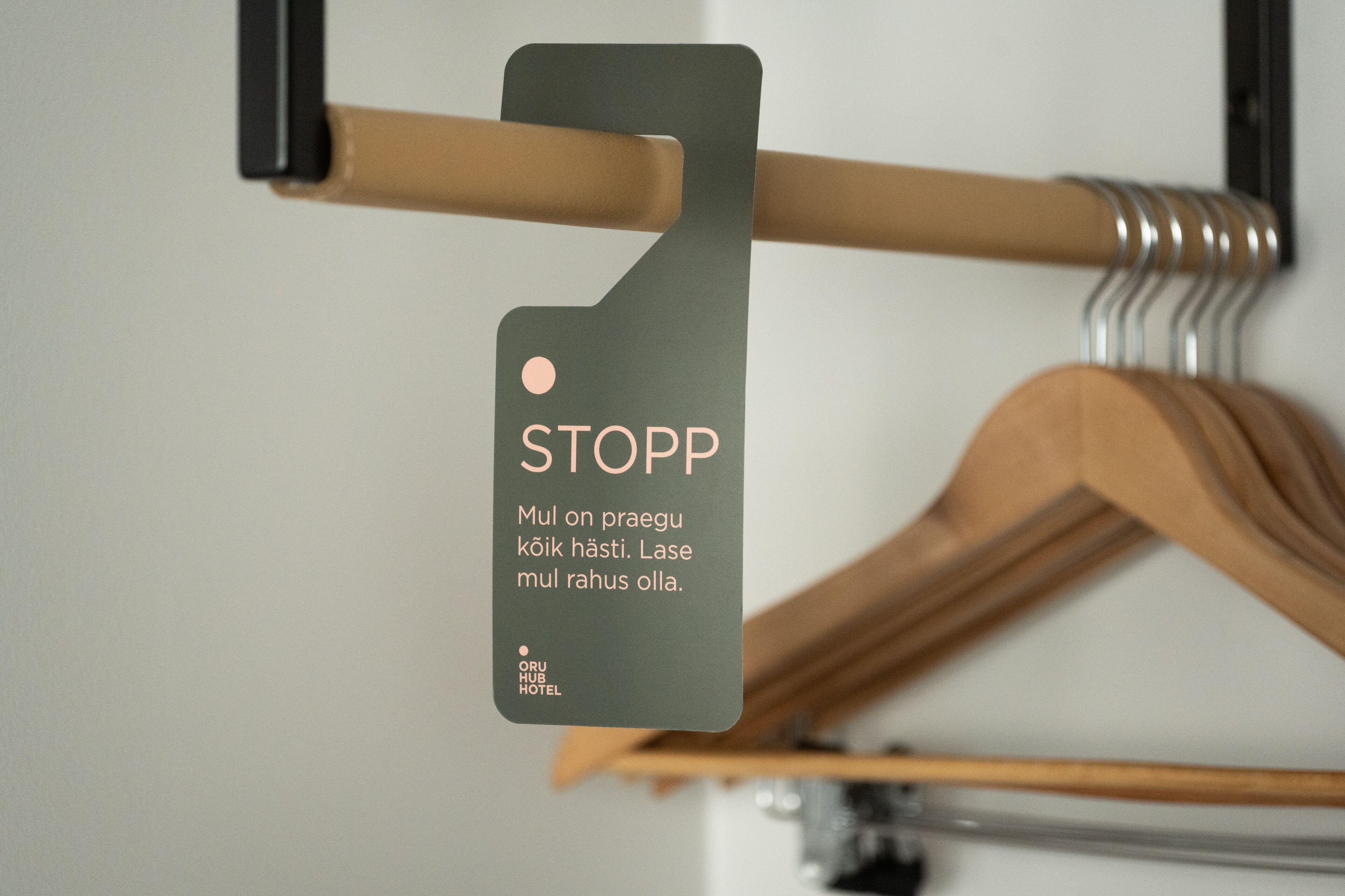 A wooden hanger with a metal clip and a tag that reads "STOPP" and "Mul on praegu kock hasti. Lase mul rahus olla."
