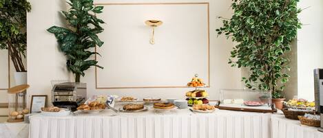 A buffet table with various food items and a decorative plant.