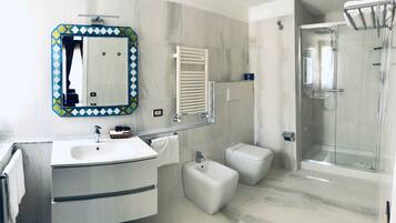 Un bagno moderno con uno specchio grande, un lavandino, un bidet e una cabina doccia in vetro.