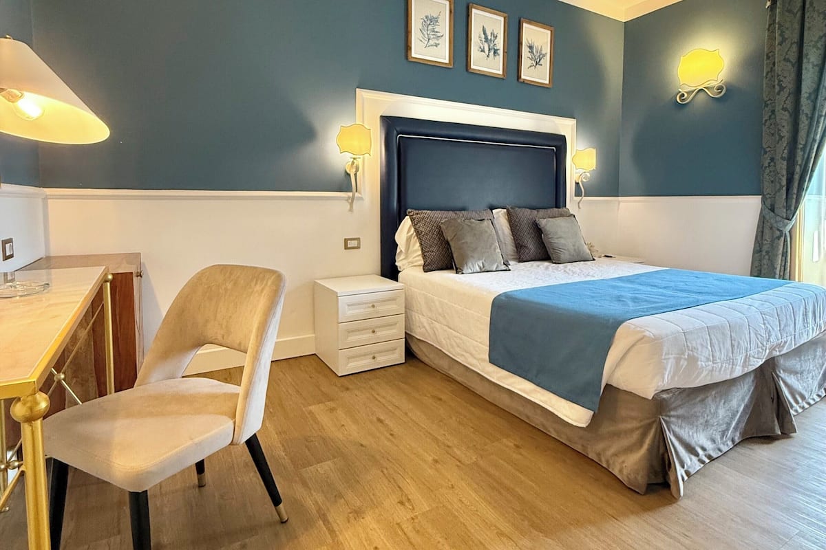 A bedroom with a bed, bedside tables, a desk, and a chair.