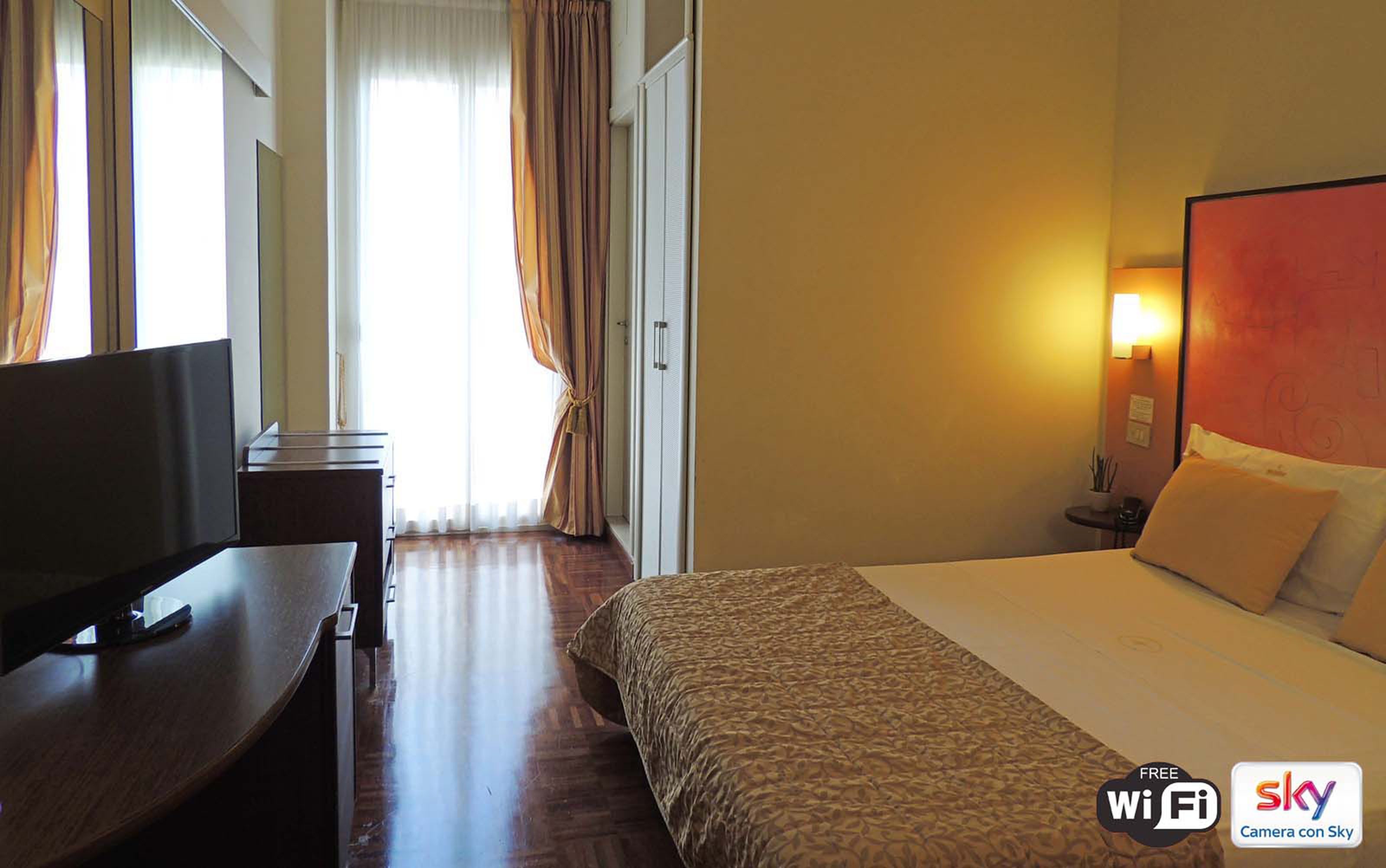 A hotel room with a bed, a desk, and a TV.