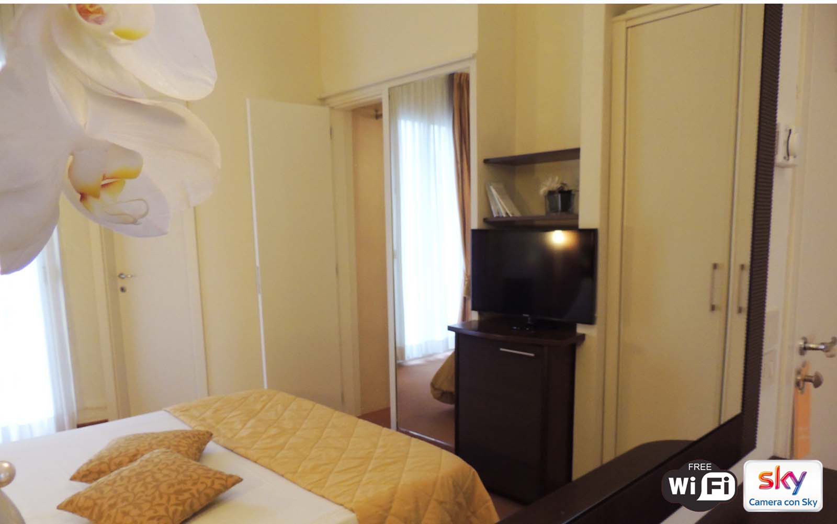 A hotel room with a bed, a television, and a wardrobe.