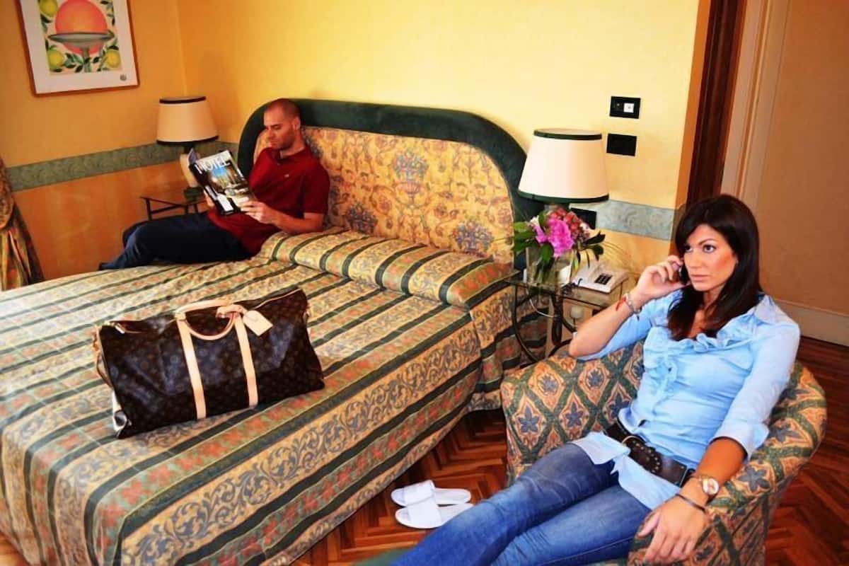 A hotel room with a bed, a nightstand with a lamp, and a chair.