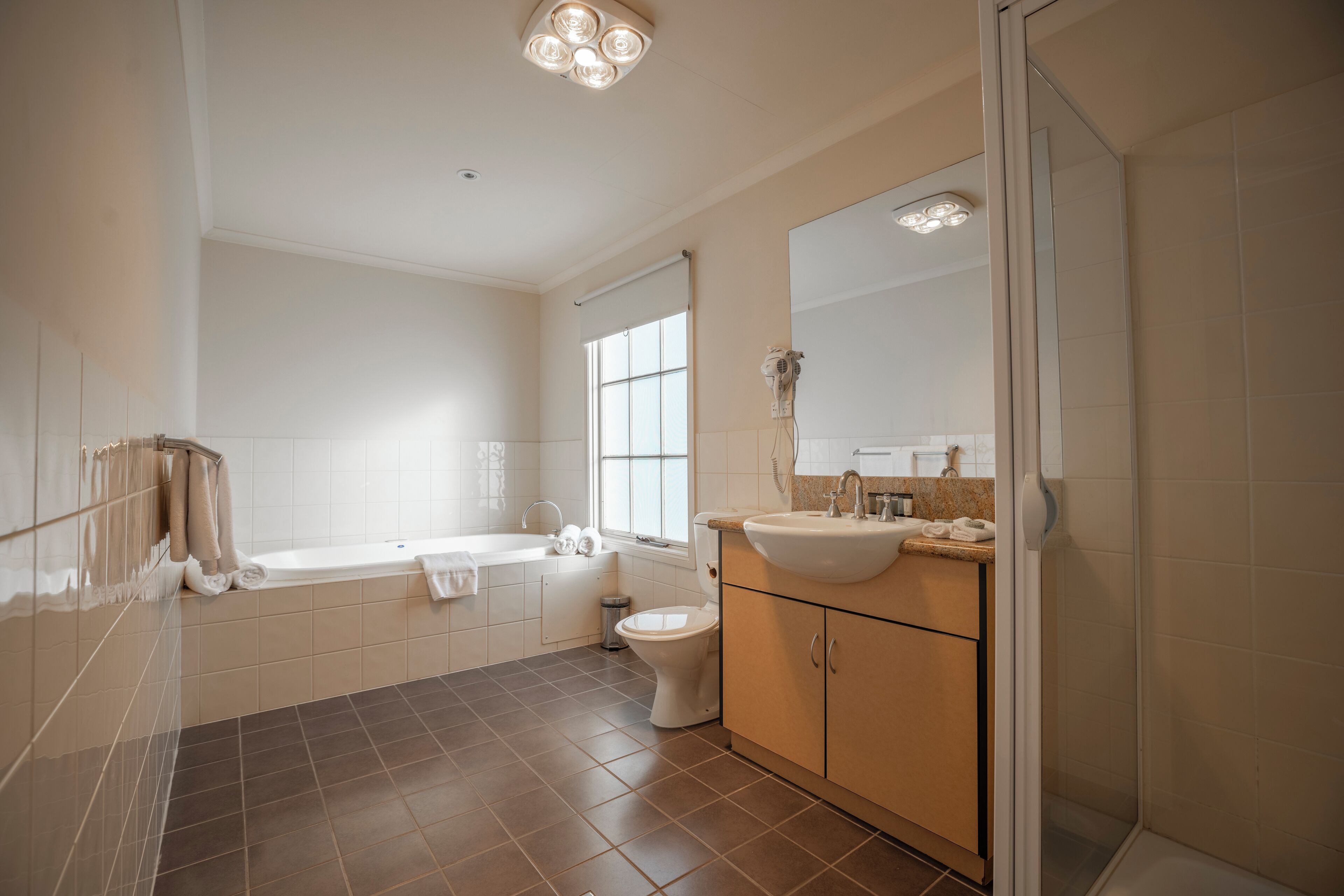 A modern bathroom with a bathtub, toilet, sink, and a large mirror.