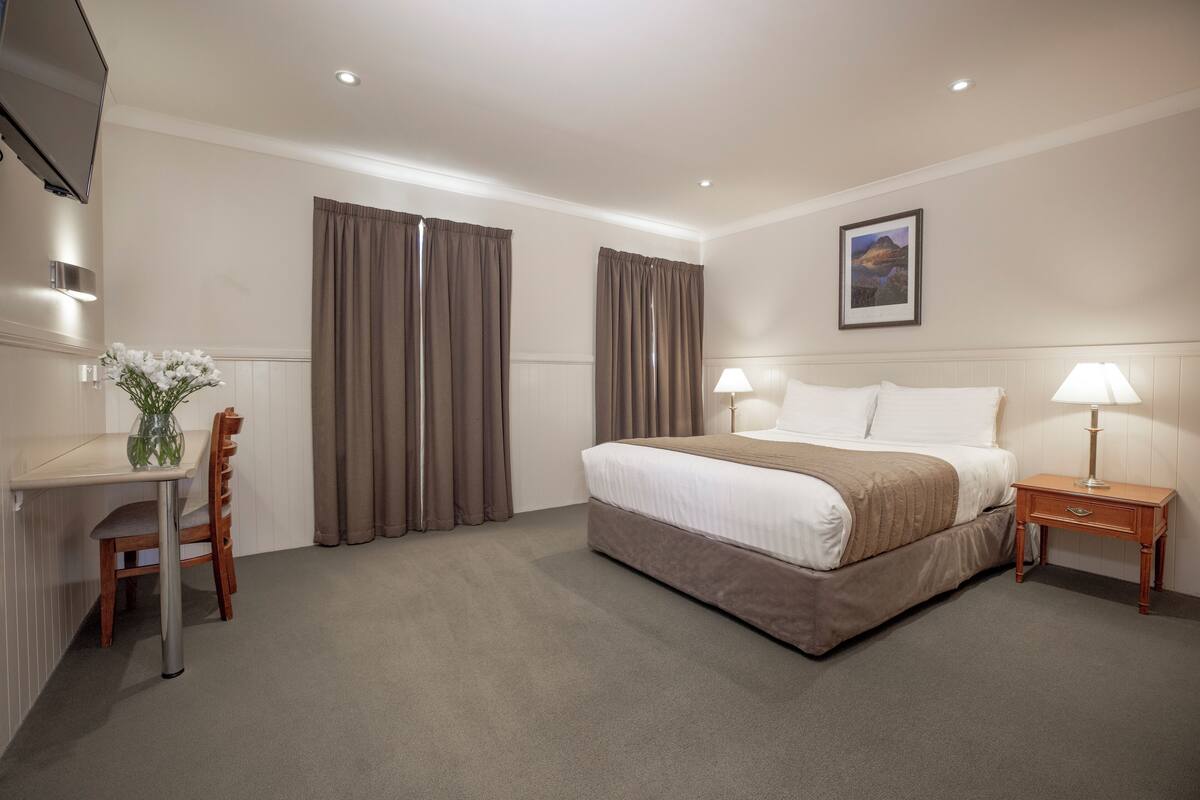 Une chambre d’hôtel comprenant un lit, des tables de chevet, un bureau et une chaise.
