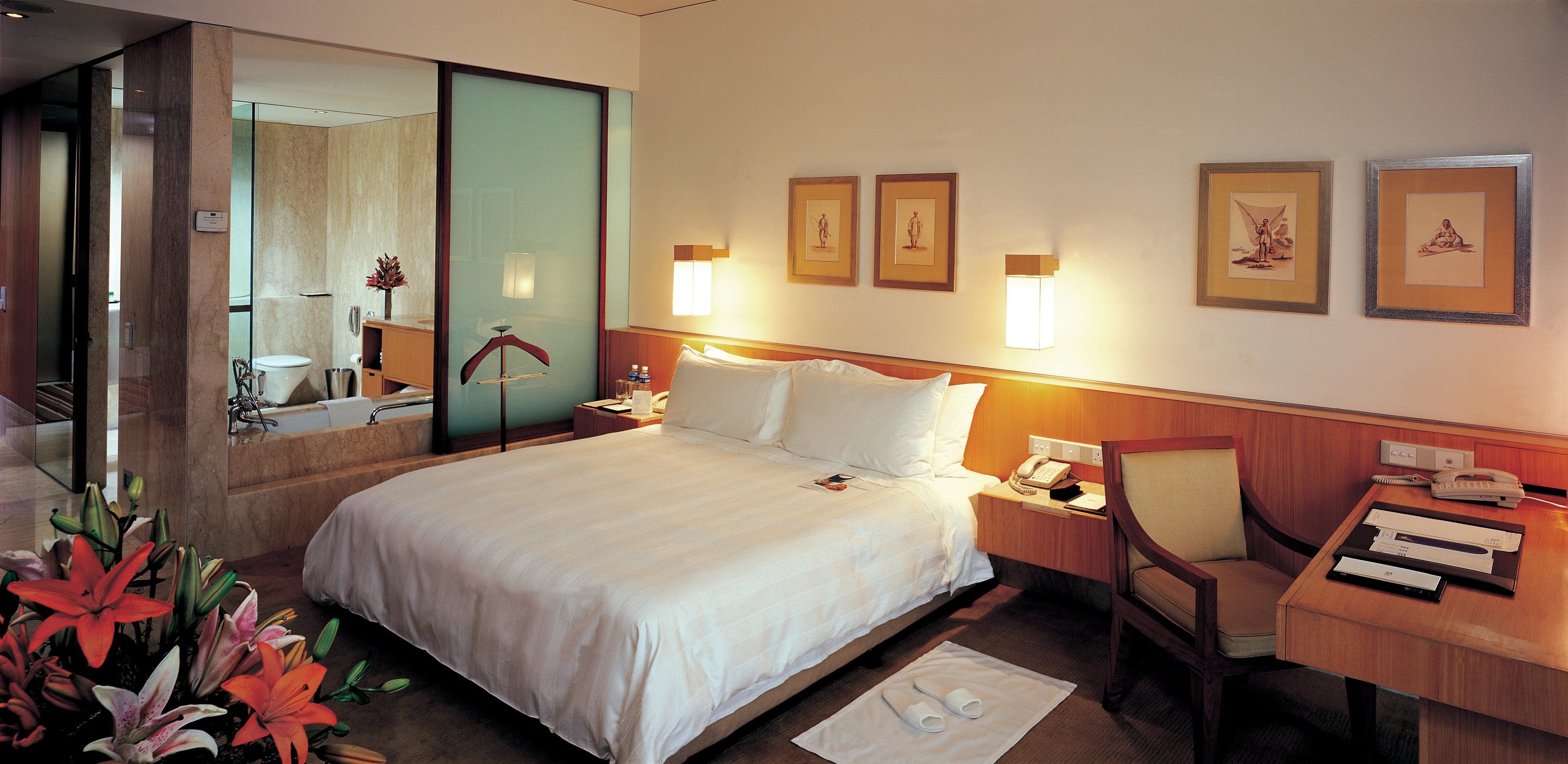 Habitación de hotel con una cama grande, un escritorio, una silla, un teléfono y un espejo.