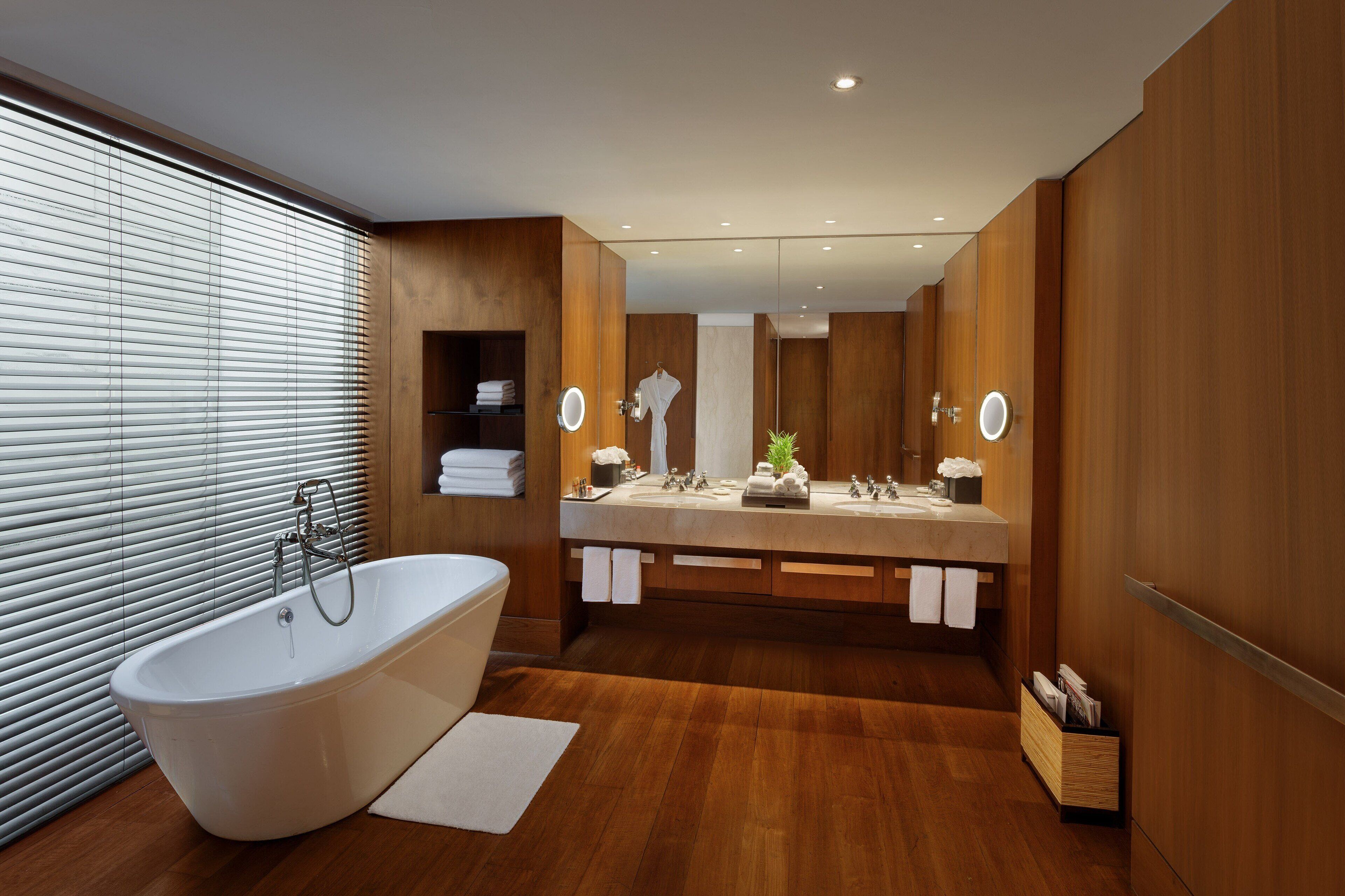 A modern bathroom with a freestanding bathtub, double sinks, and a large mirror.
