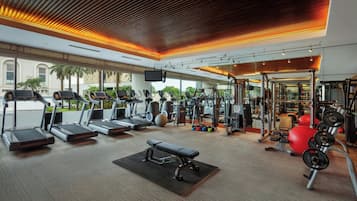 A modern gym with treadmills, a bench, weight machines, and a variety of exercise equipment.
