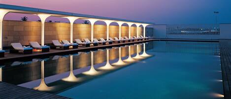A poolside area with sun loungers and a covered seating area.