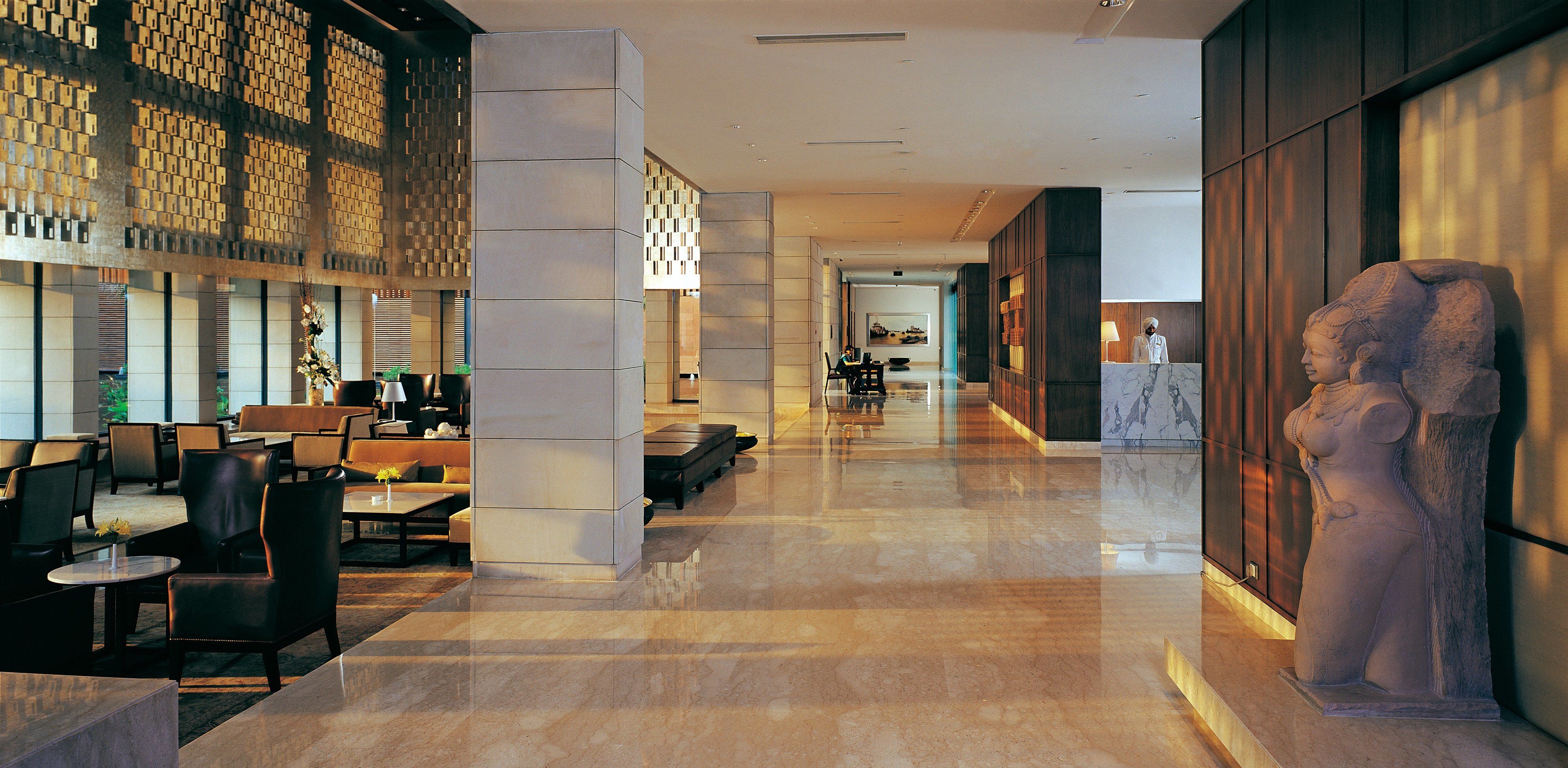 A modern lobby with a marble floor, seating areas, and a large stone sculpture.