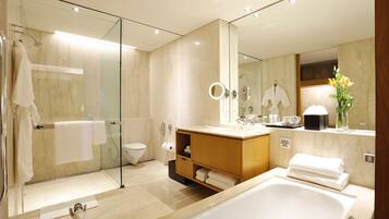 A modern bathroom with a glass-enclosed shower, a large bathtub, and a vanity with a mirror.