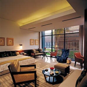A modern hotel room with a large bed, a sofa, two armchairs, a coffee table, and a view of the outdoors through large windows. - ITC Sonar, a Luxury Collection Hotel, Kolkata (Kolkata)