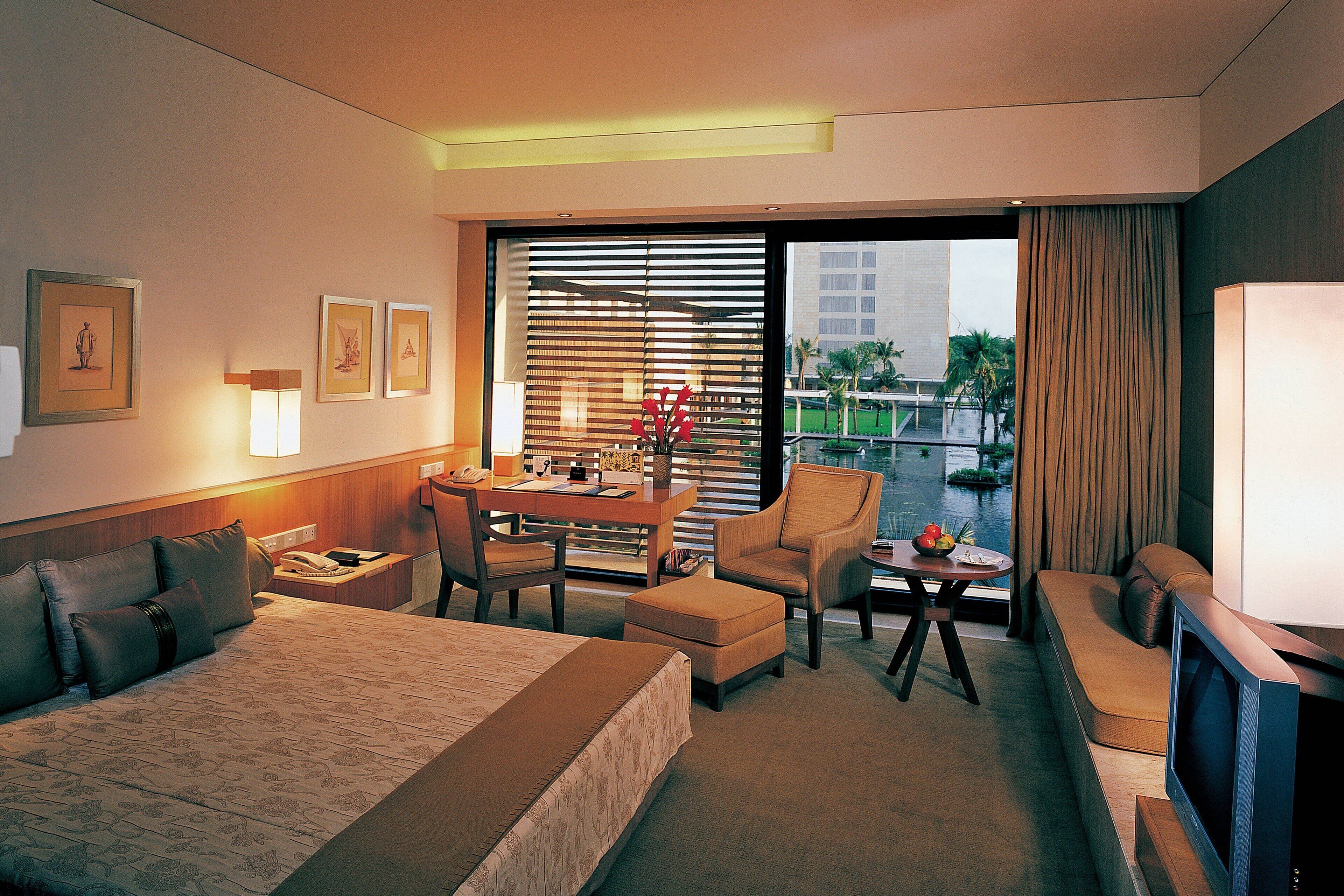 A hotel room with a bed, a desk, a chair, a sofa, and a TV.