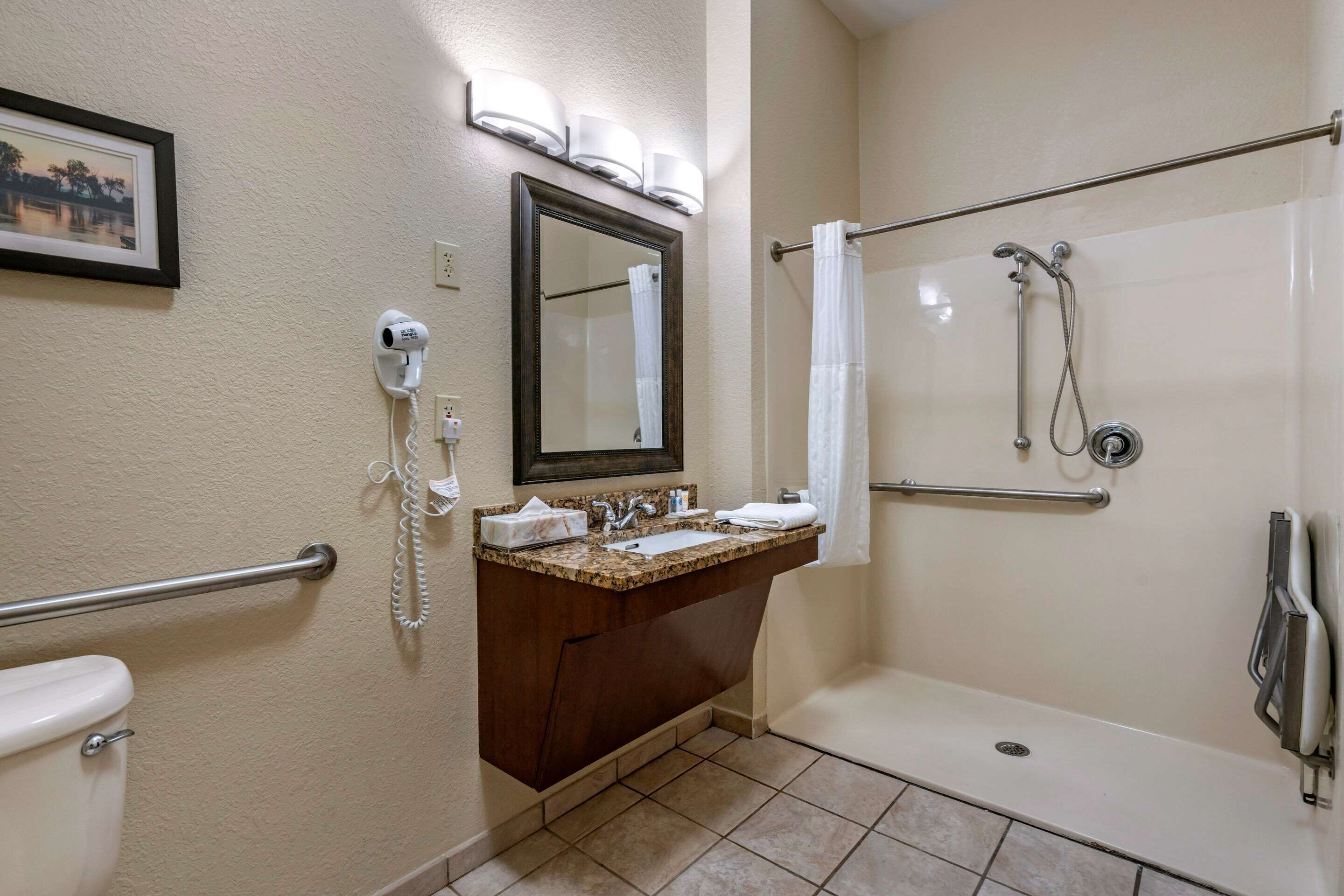 A bathroom with a toilet, sink, mirror, and shower.