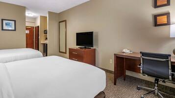 A hotel room with two beds, a desk, a chair, a television, and a mirror.
