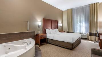 A hotel room with a large bed, a separate bathroom with a bathtub, and a desk with a chair.