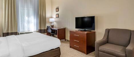 A hotel room with a bed, a desk, a chair, a television, and a lamp.
