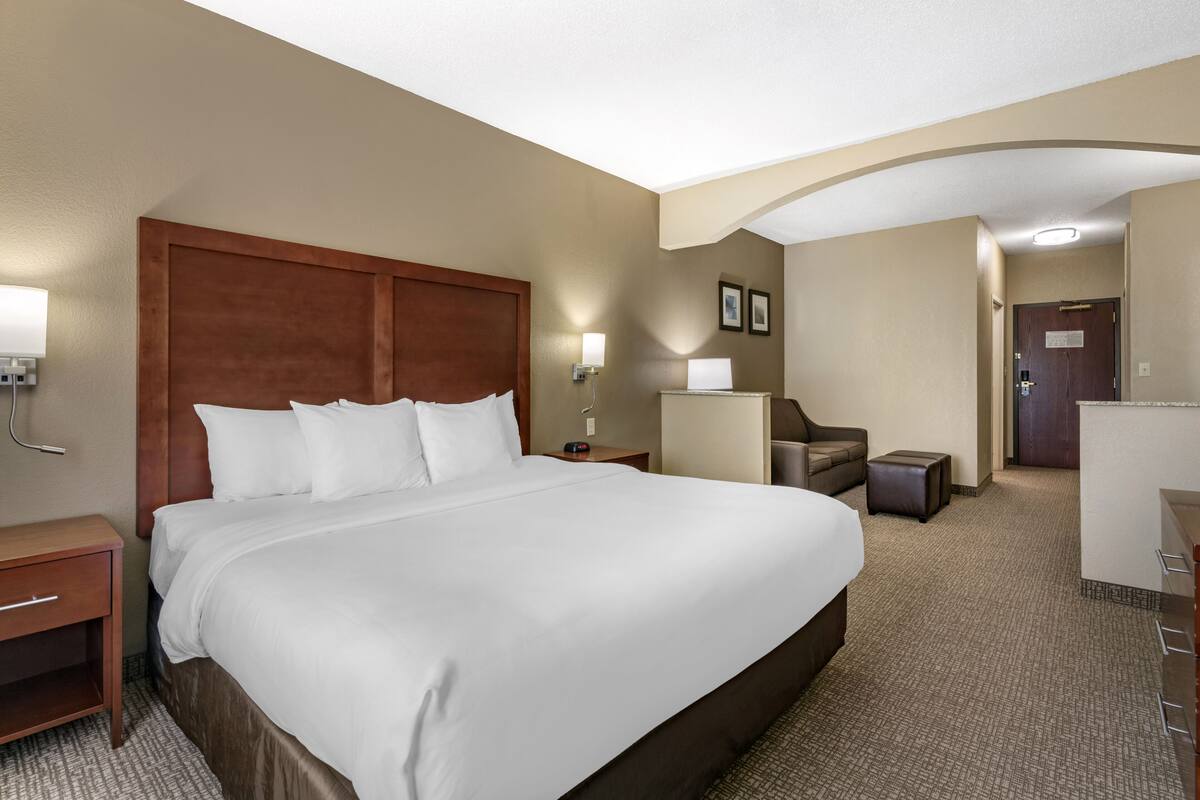 A hotel room with a large bed, a desk, a chair, and a small table.
