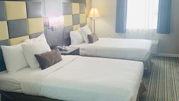 A hotel room with two beds, a headboard with a checkered pattern, a bedside lamp, and a window with curtains.