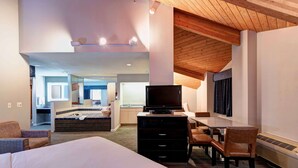 A hotel room with a large bed, a desk with a flat-screen TV, a chair, a dresser, and a small kitchenette area. - SureStay Plus Hotel by Best Western Redding (Redding)