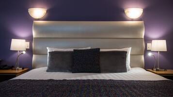 Una cama bien hecha con una colcha a rayas y dos almohadas, con dos lámparas de noche de madera a cada lado.