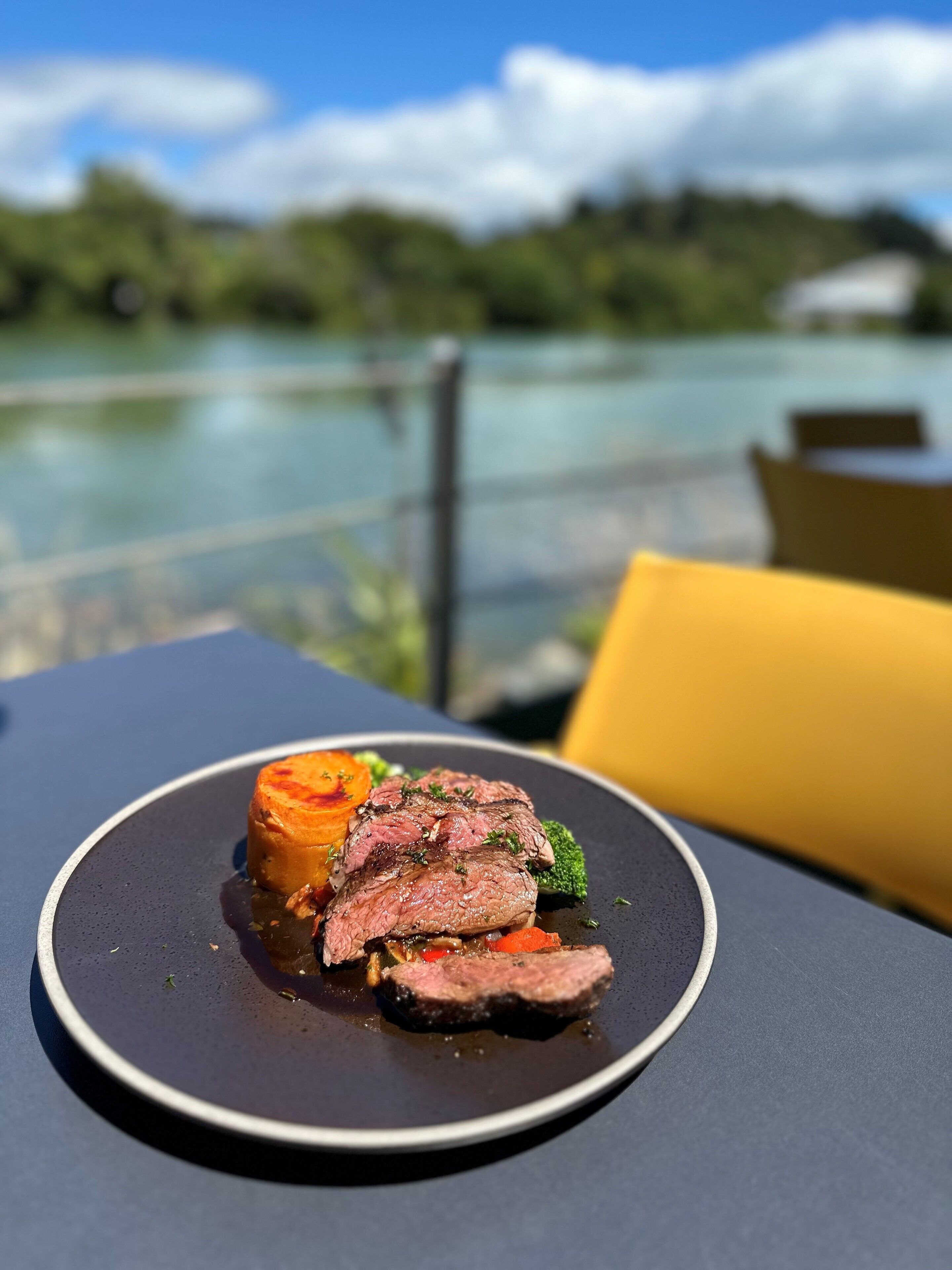 Un plato de comida con vistas a un lago y follaje al fondo.