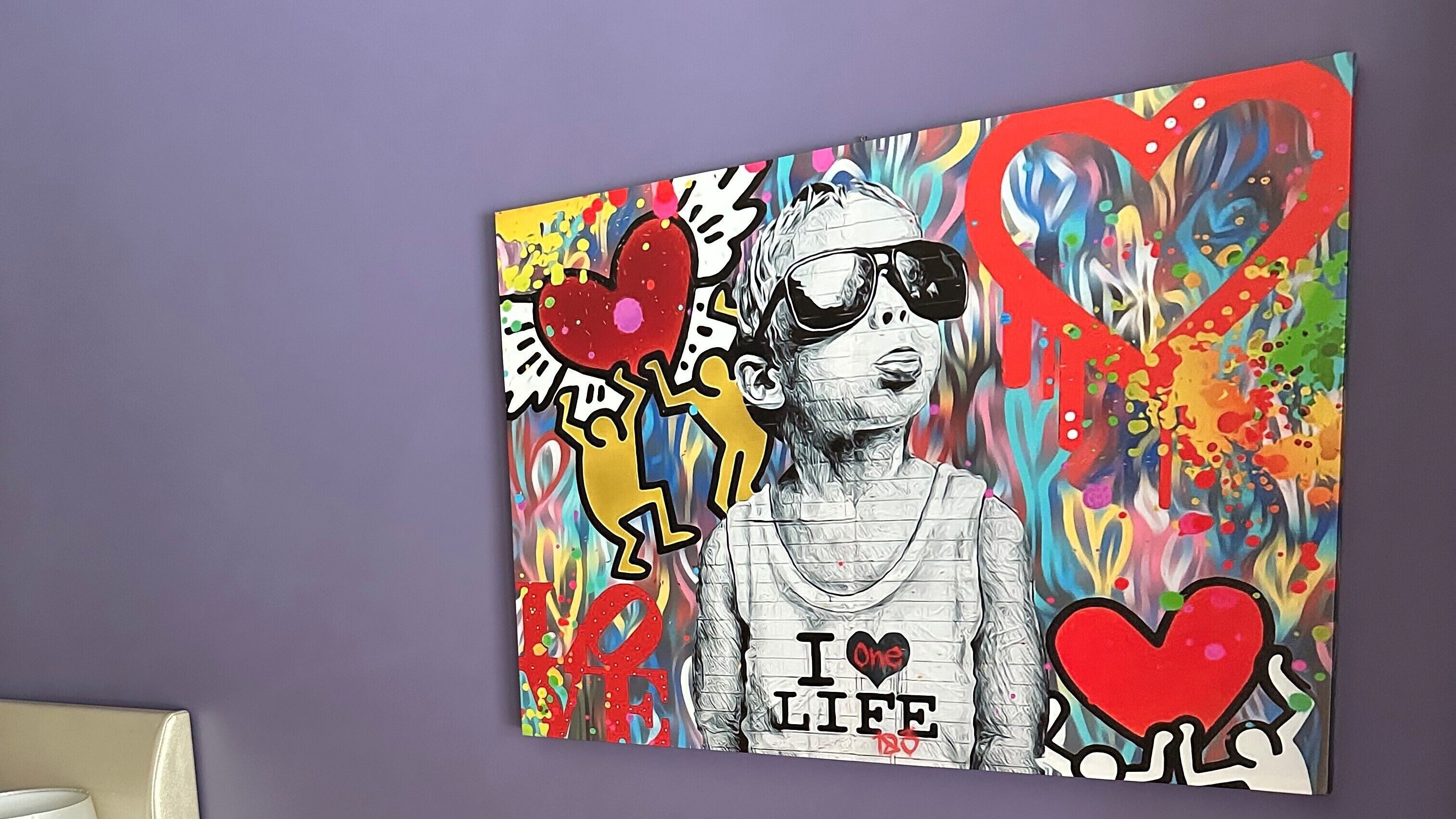 A vibrant artwork with abstract elements and text on a wall.