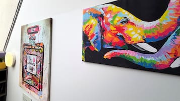 Due opere d'arte su una parete, una raffigura un elefante colorato e l'altra un poster in stile graffiti.