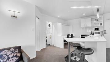 A modern kitchen with white cabinetry, a central island with bar stools, and a built-in microwave.