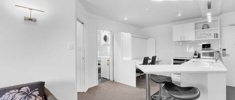 A modern kitchen with white cabinetry, a central island with bar stools, and a built-in microwave.