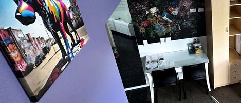 Une pièce avec un mur violet, un bureau blanc et un meuble en bois.