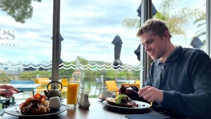 A person dining at a table with a view of the sky and buildings. - Tides Hotel (Nelson)