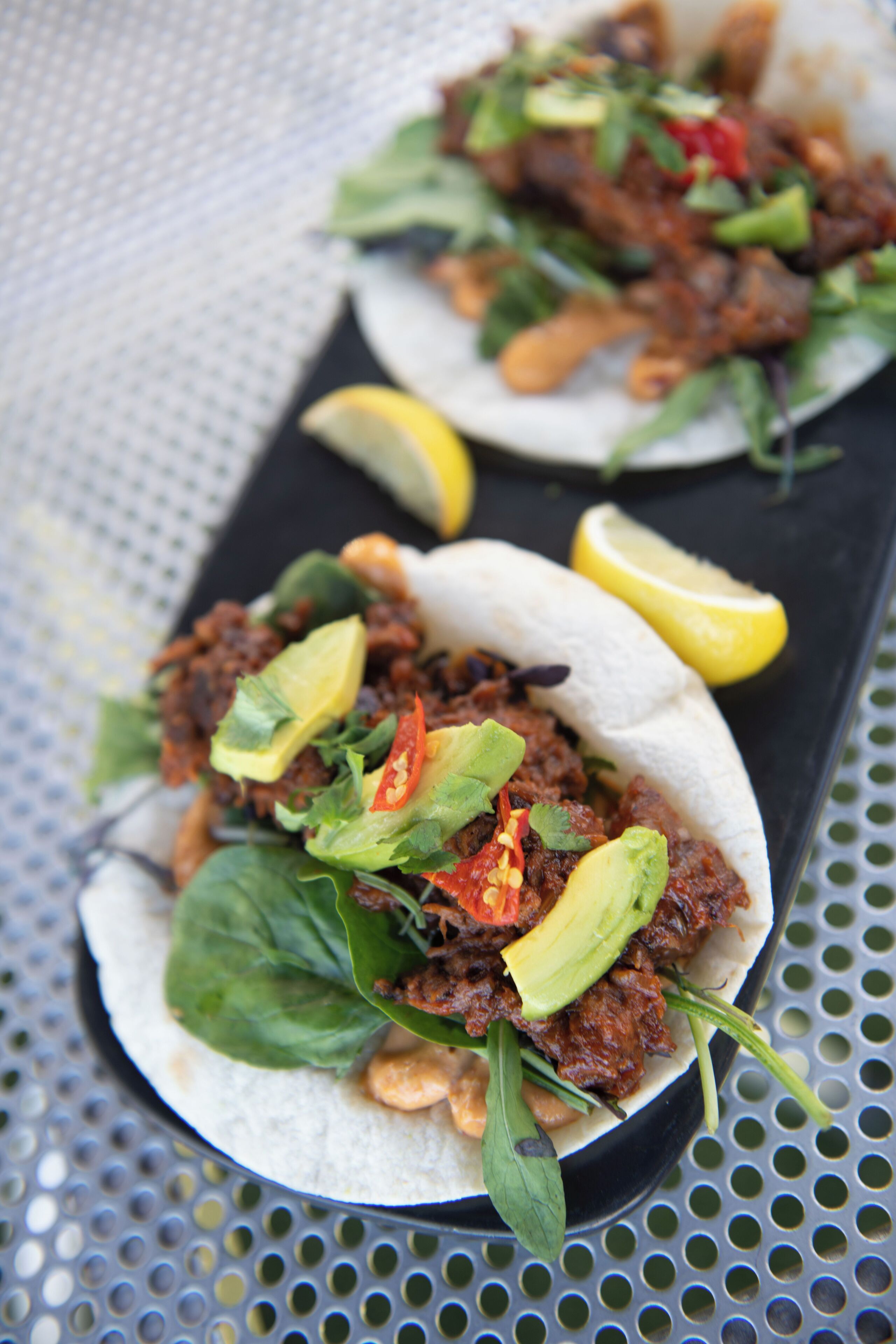 A plate of tacos with avocado, lettuce, and red peppers.