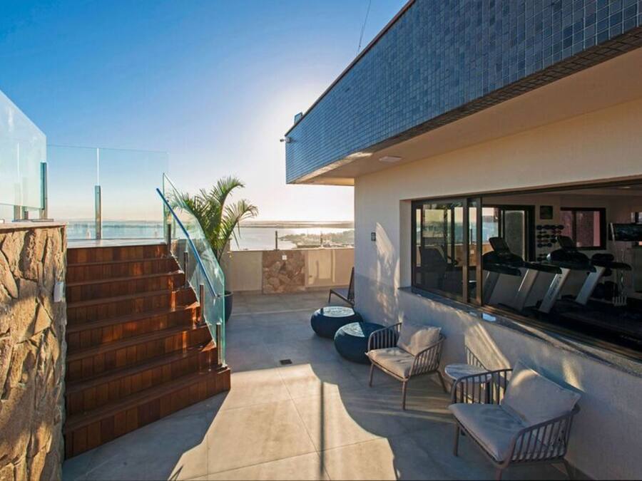Eine moderne Terrassenanlage im Freien mit einer Steintreppe, einer Sitzgelegenheit und Blick auf den Ozean.