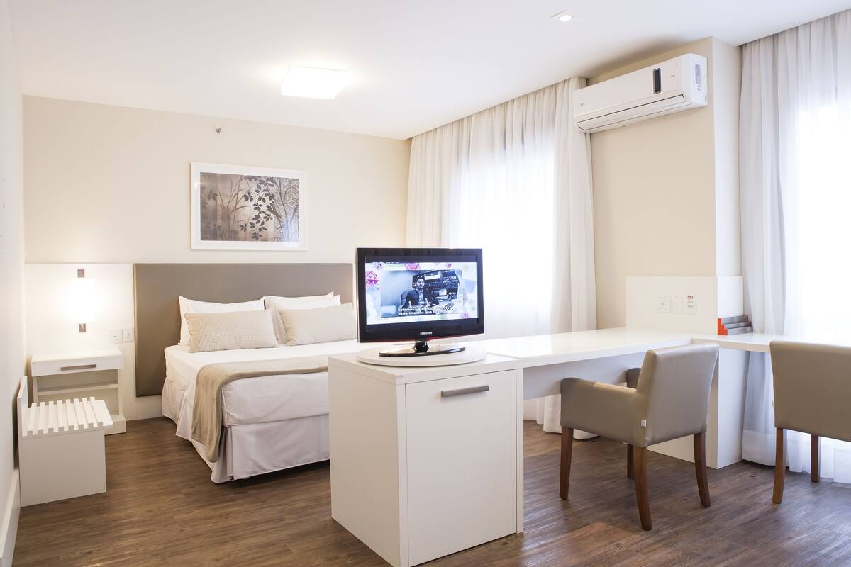 Een moderne hotelkamer met een bed, bureau en televisie.