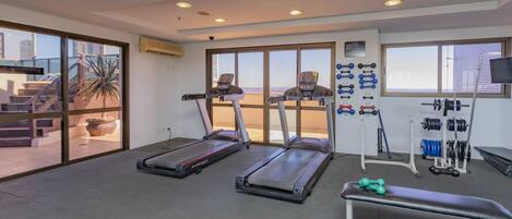 A gym with treadmills, a bench, dumbbells, and a weight rack.