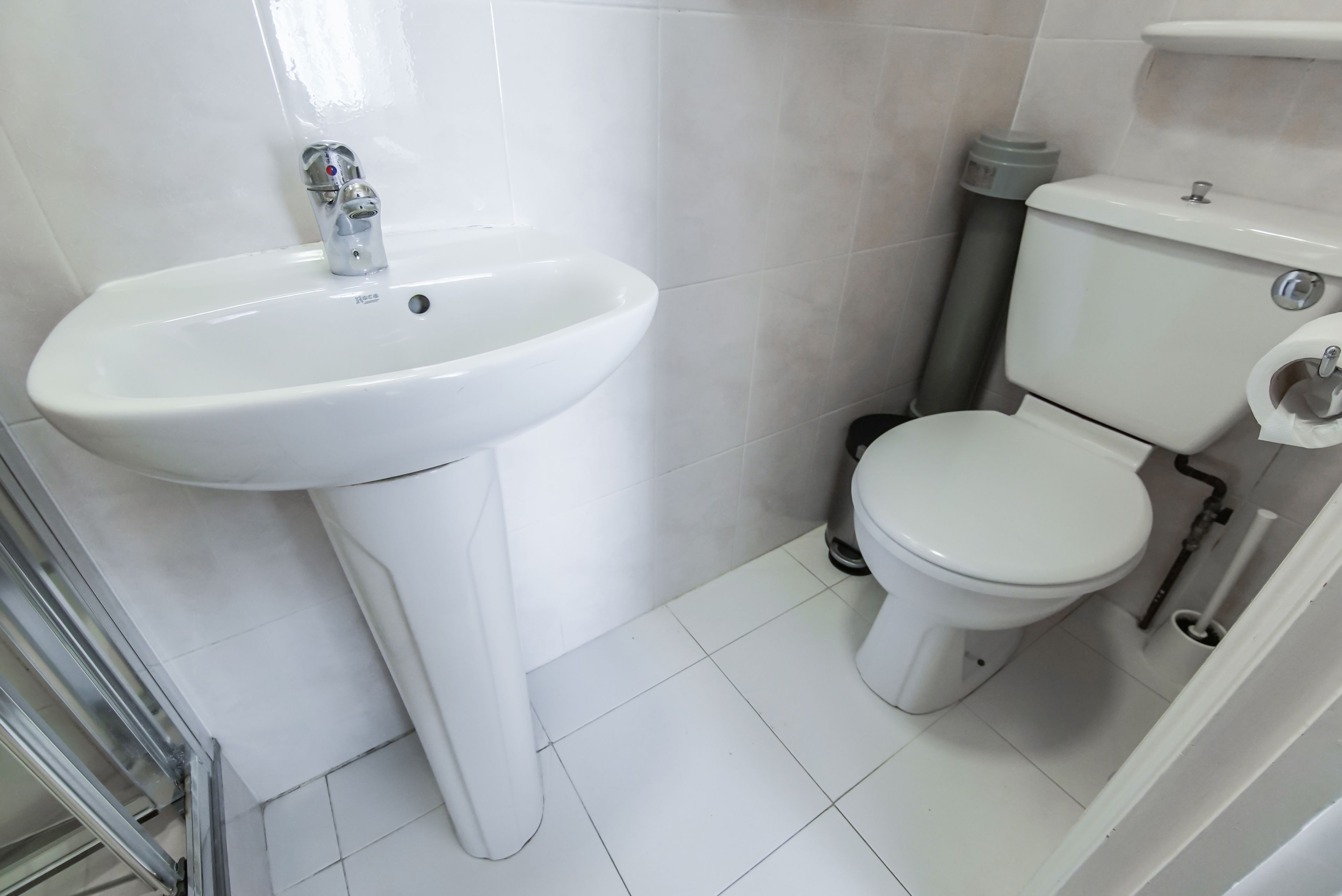 A bathroom with a white sink, toilet, and tiled floor.