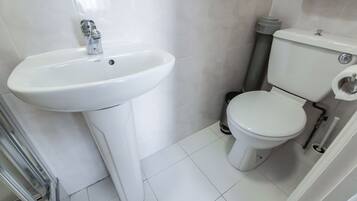 A bathroom with a white sink, toilet, and tiled floor.