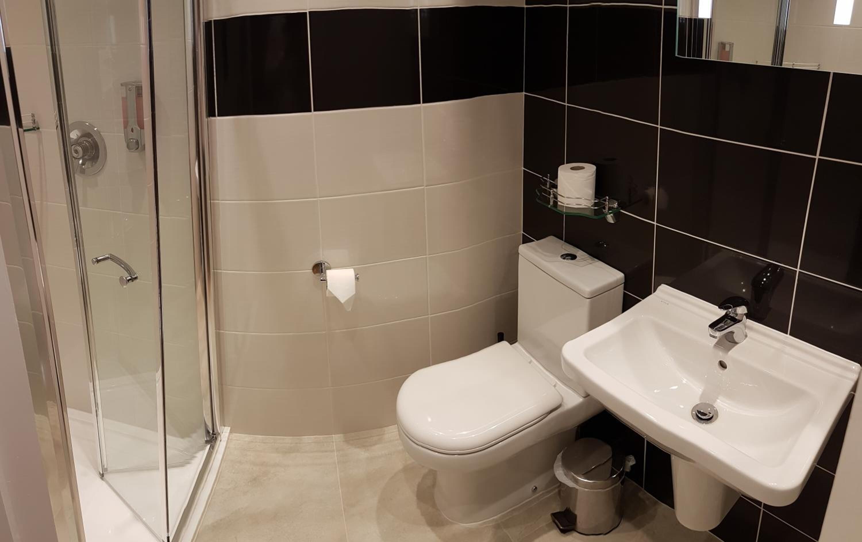 A bathroom with a glass shower enclosure, a toilet, and a sink.