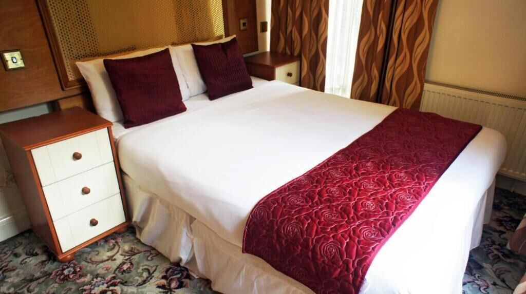 Ein Hotelzimmer mit einem großen Bett, einem Nachttisch und einem Teppich mit Blumenmuster.