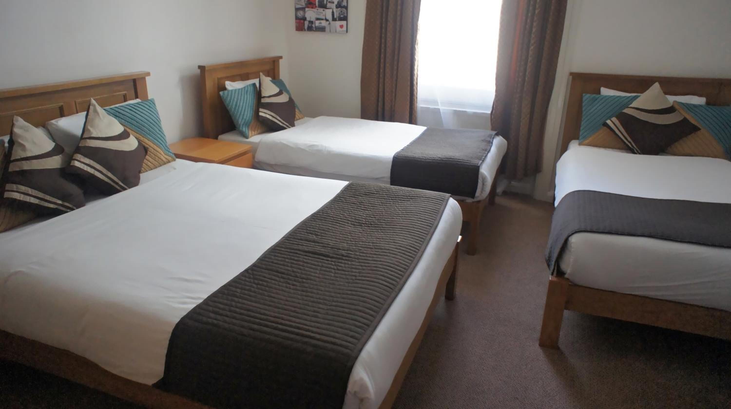 A hotel room with two single beds, each with a wooden headboard, white bedding, and multiple pillows.