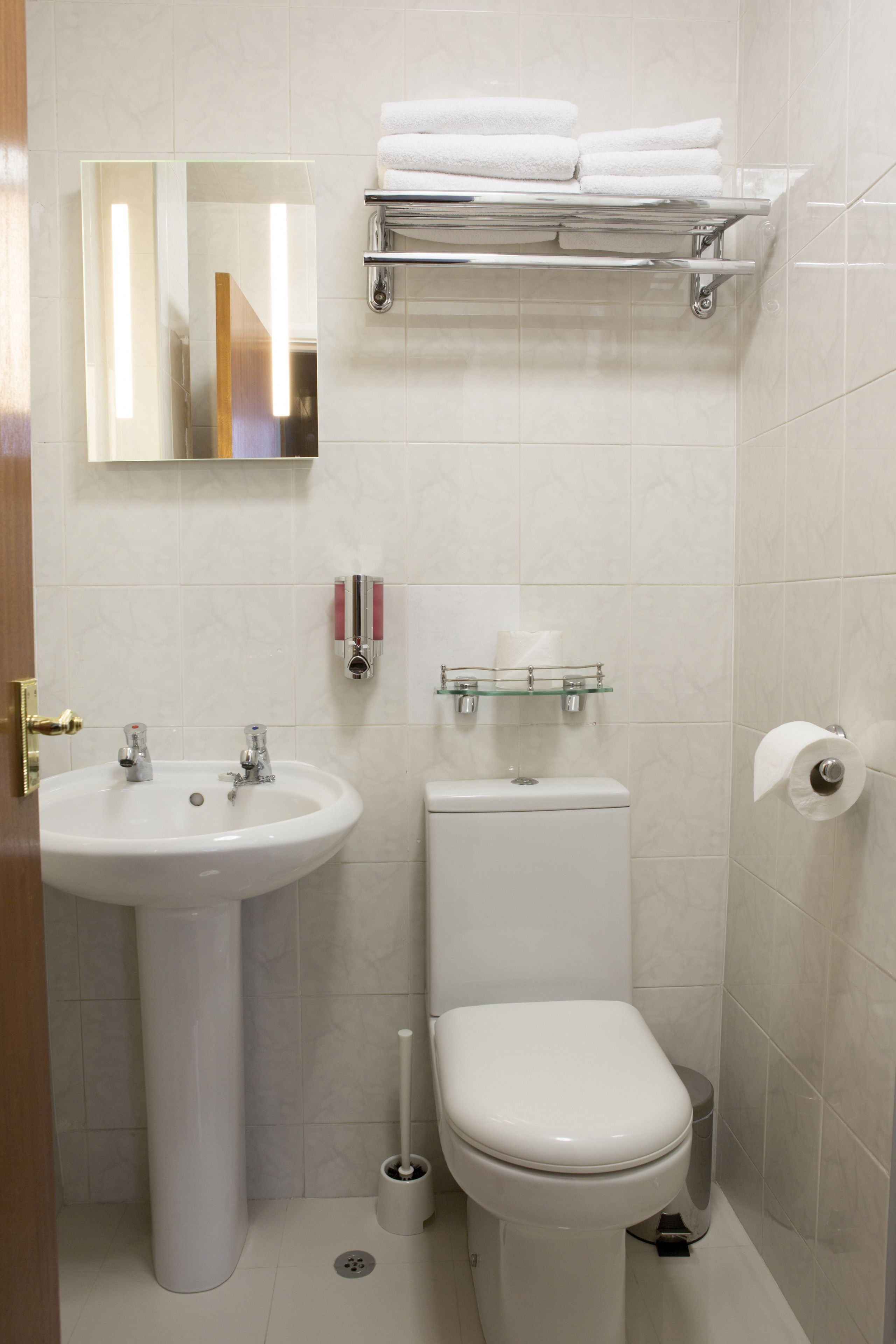 A bathroom with a sink, toilet, and a shelf with towels.
