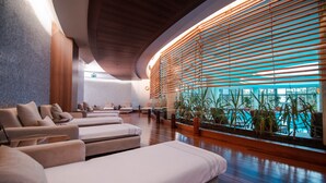 A spa area with multiple massage beds, wooden paneling, and a view of the pool.