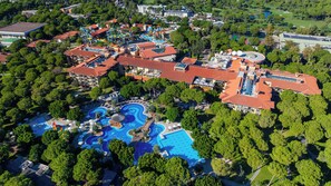 An aerial view of a resort with multiple swimming pools, a water park, and a variety of buildings with red-tiled roofs. - Gloria Golf Resort - All Inclusive (Serik)